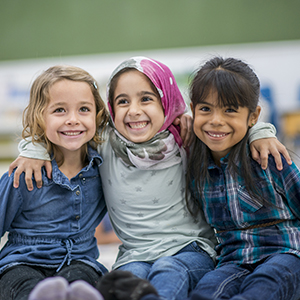 Three schoolgirls smiling in a classroom