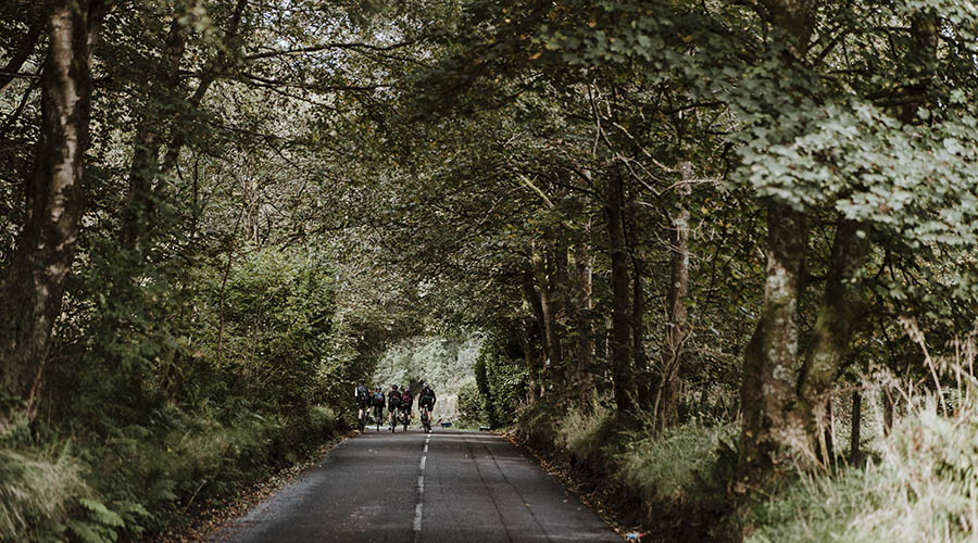 Group of cyclists riding along a country road. 
