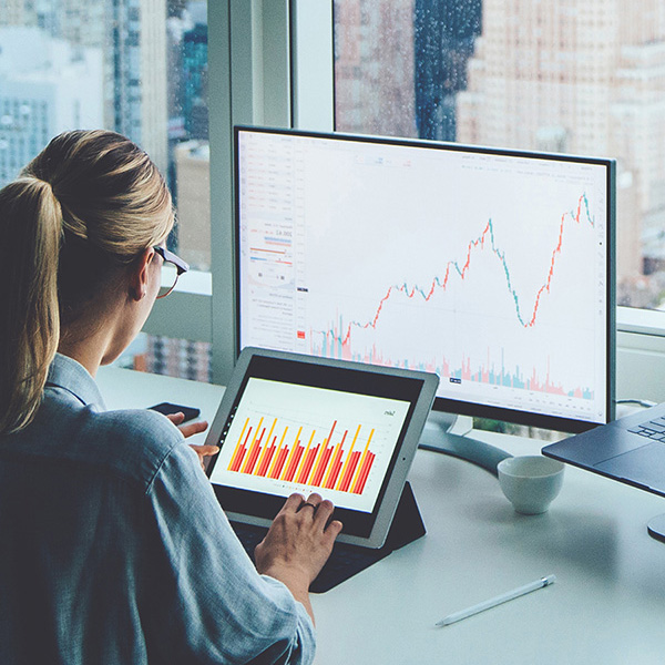 Woman sitting at a computer looking at finance reports 