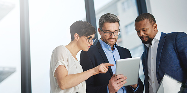 Team of colleagues work together in an office with a tablet.