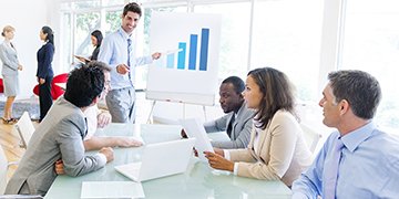 Business people sit around a desk to plan activity.