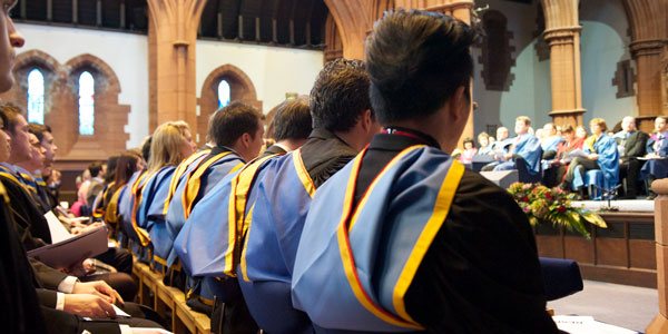 back view of a row of students facing the stage at graduation