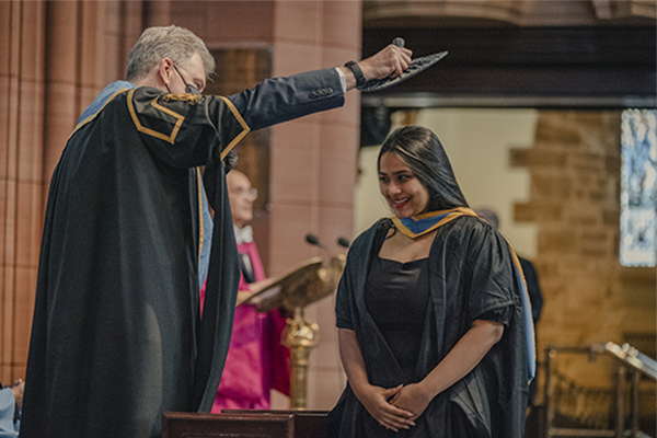 Student on stage being capped at the Graduation ceremony in Barony Hall.