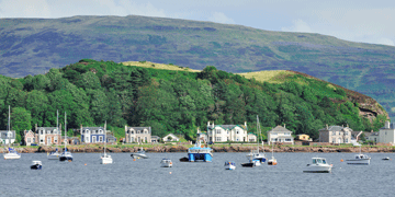 A view of millport from the water - boats on the water with boats and houses onshore