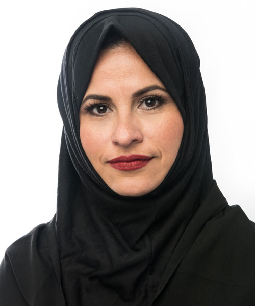A woman in a headscarf smiles at the camera