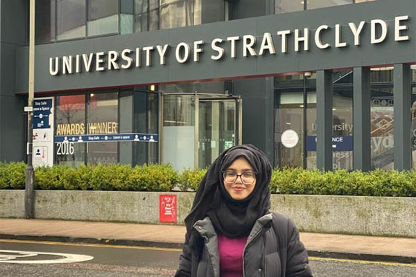 Alina Ashraf standing in front of the University of Strathclyde sign.
