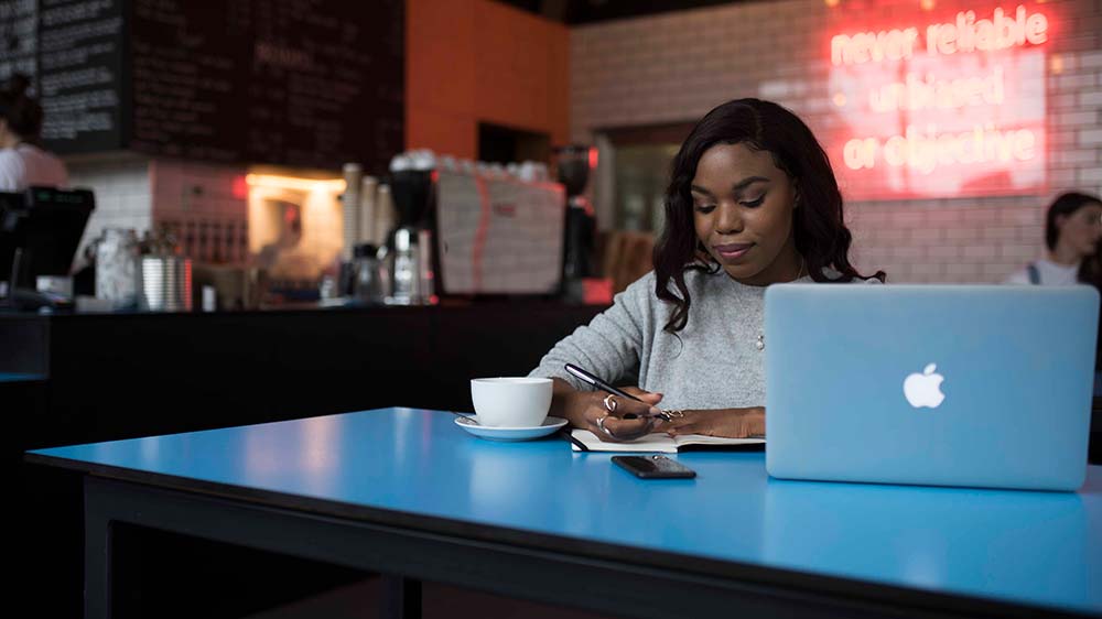 Student in cafe working on laptop.