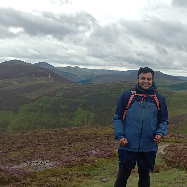 Aditya Prakash outside with hills visible in the distance behind