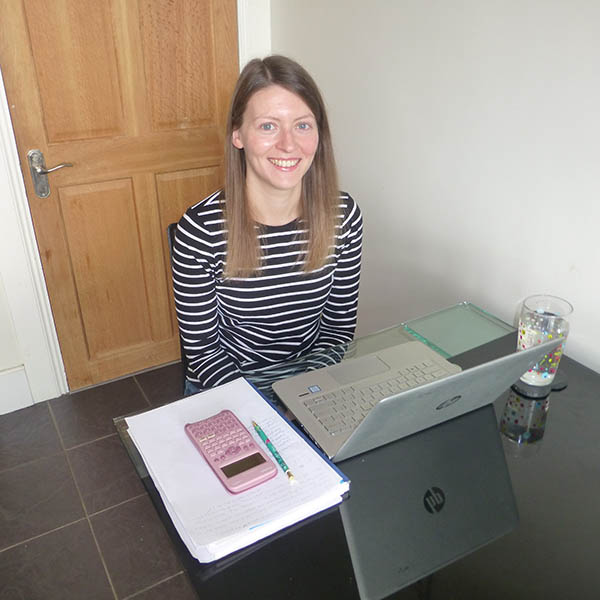 Lesley Thomson, postgraduate student with laptop and calculator at home
