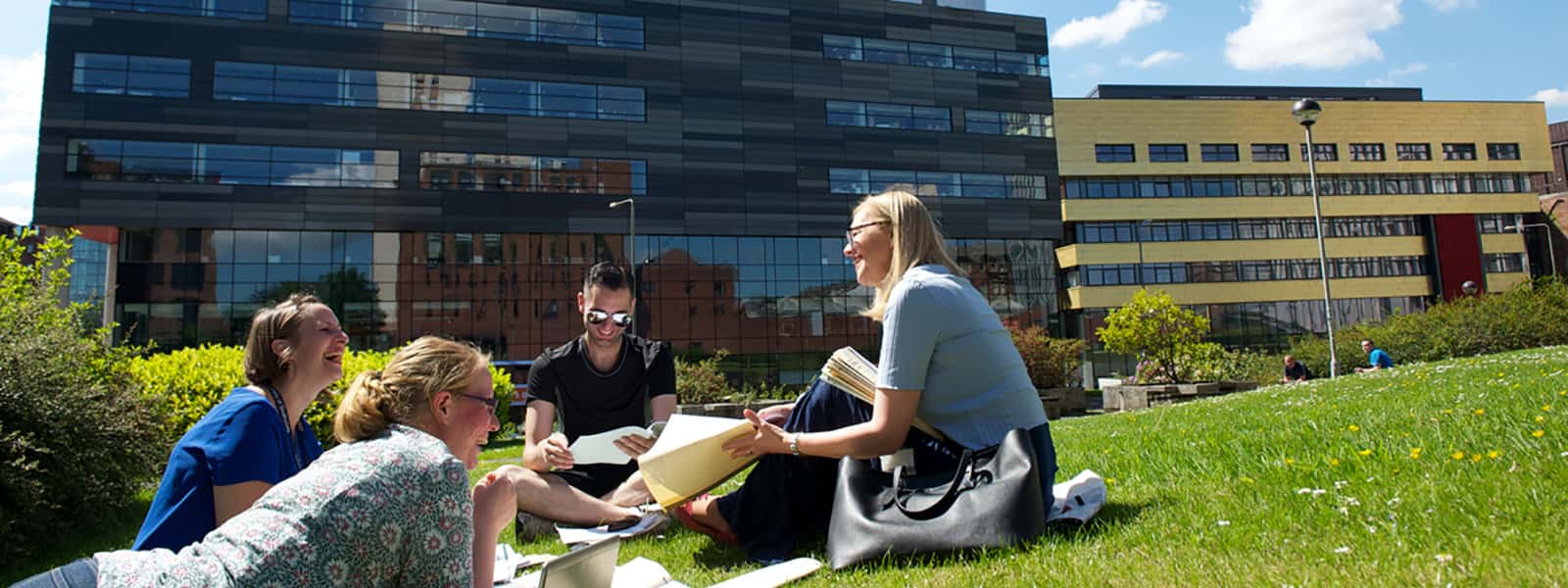 Four students sitting on the grass on campus