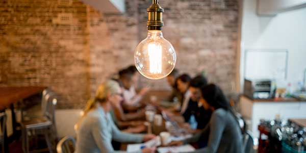 Group of business people brainstorming at a creative office and a light bulb in the foreground