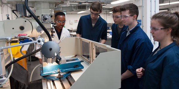 a lecturer teachers engineering students how to use a large machine