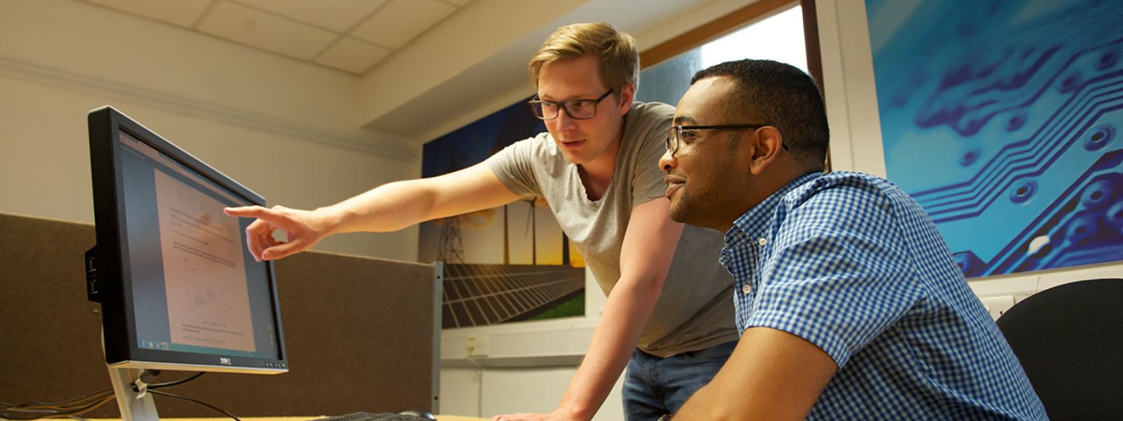 Postgraduate students looking at a computer screen