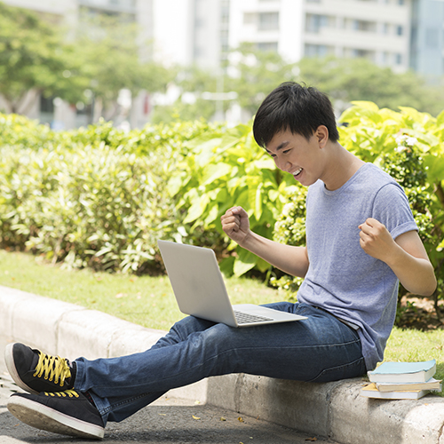 Student sitting outside looking at a laptop