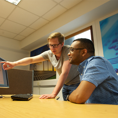 Postgraduate students looking at a computer screen