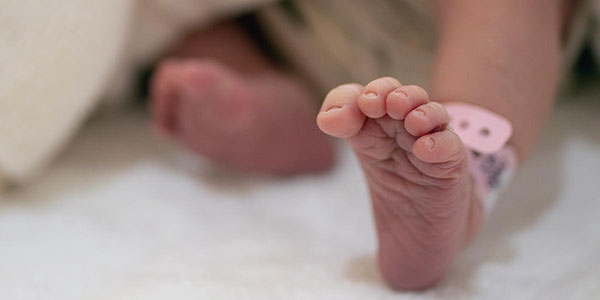 Closeup of baby's foot in a hospital with tag on ankle.