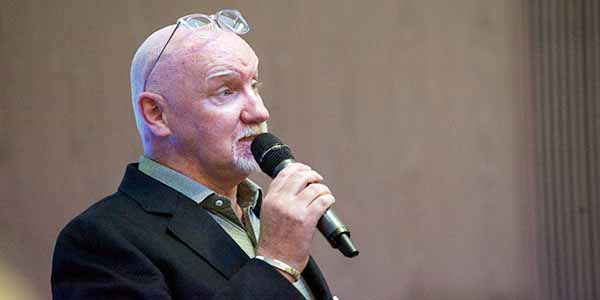 Tom Hunter holding a microphone, talking to an audience