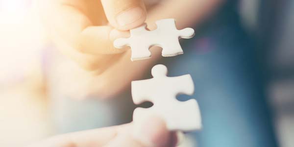 Hand of two people holding jigsaw puzzle connecting together. 