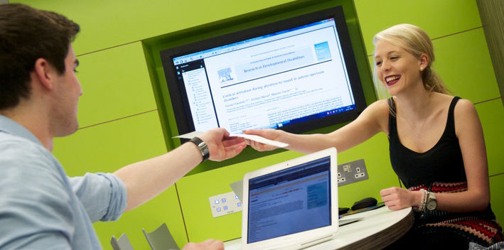 Two students in library, green background, male and female students.