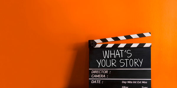 a movie clapperboard sits against an orange background
