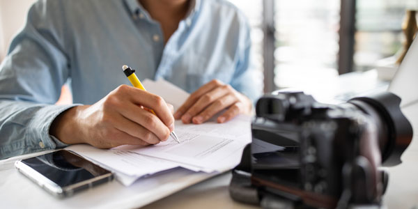 man signing a contract with a camera in the foreground