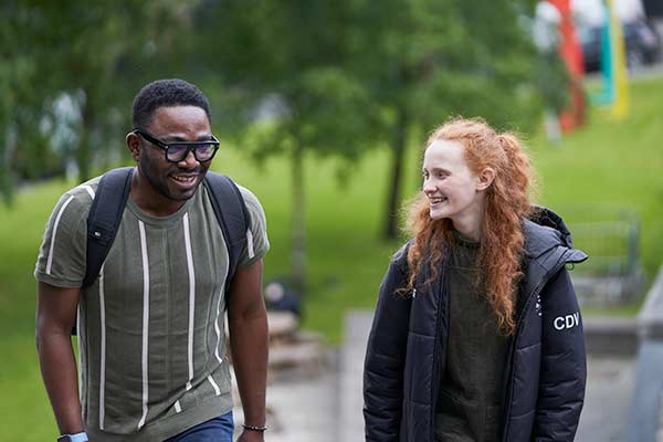 Two students walking through Rottenrow Gardens.