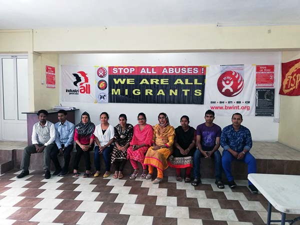 People sitting in a row under a banner which says, 