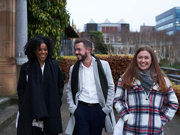 Three people walking through Rottenrow Gardens.