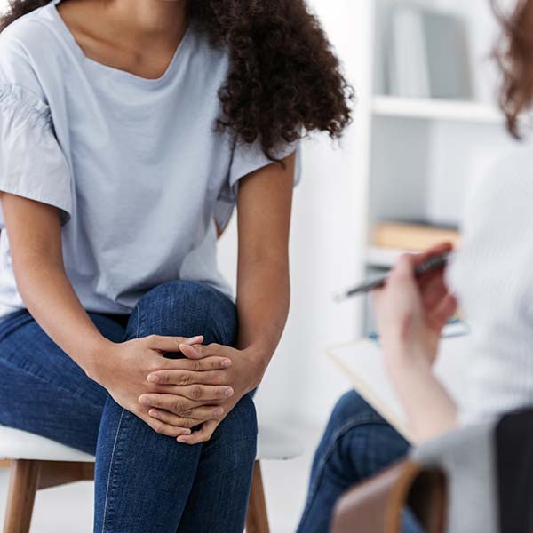 Person during a counselling session, with their legs and hands crossed.