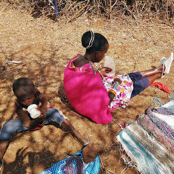 Child sitting on the ground drinking out a bottle in Keyna.