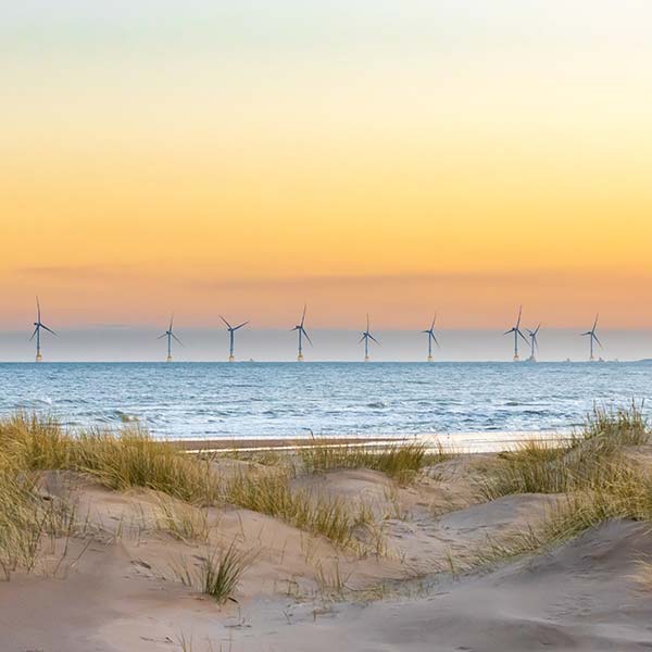 Offshore windfarm in the distance with sand dunes in the foreground.