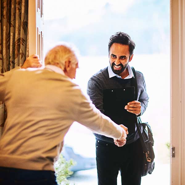 Elderly person welcome social worker into house.