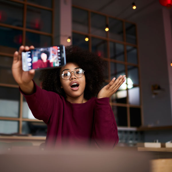 a young woman holds her phone up in front of her while she records herself talking