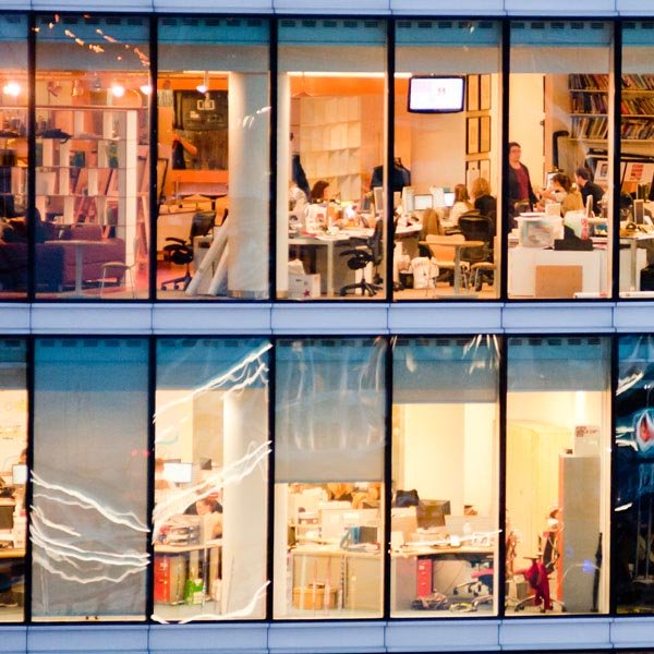 View of office building looking through the window to staff at desks