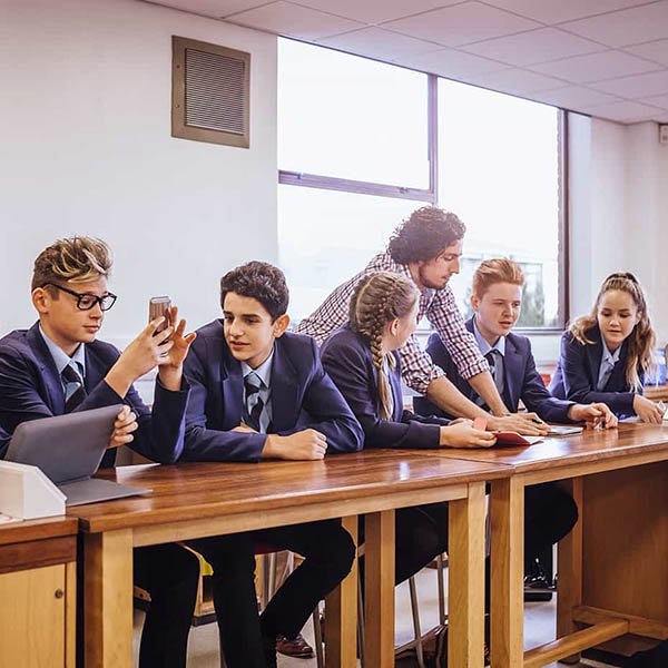 Teenage students with their teacher sat at a table in the science lab.