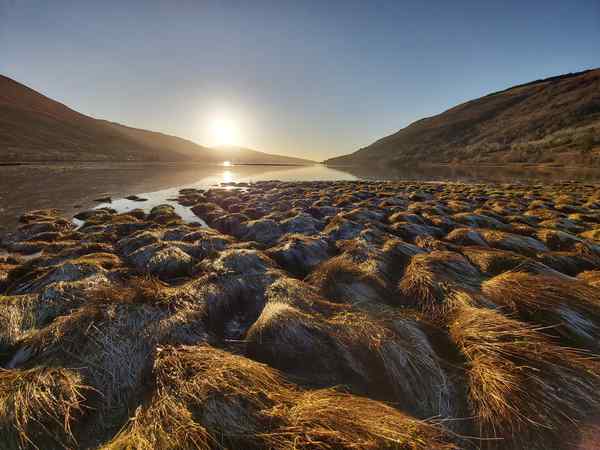 Sun shining over hills and a loch