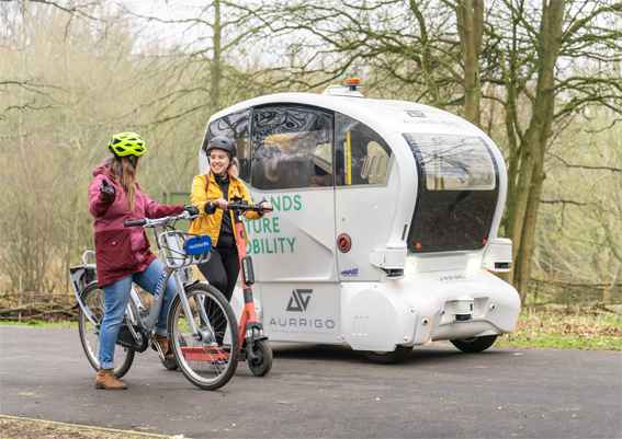 Two cyclists alongside a futuristic vehicle