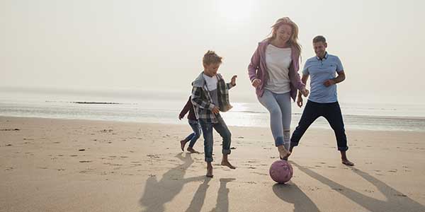A family playing football (soccer) on the beach