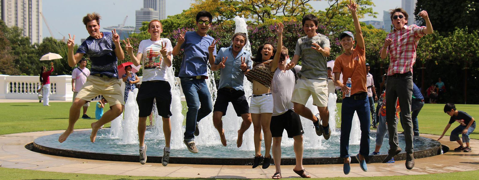 students jumping in front of fountain