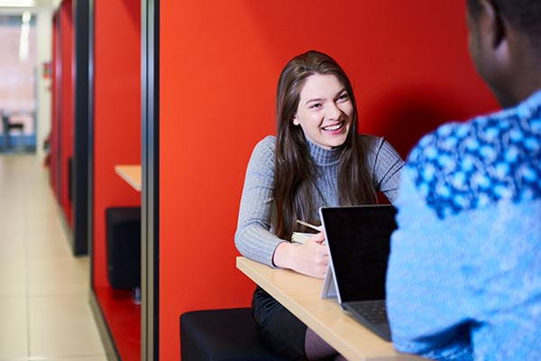 Two students sitting in a study booth in happy conversation