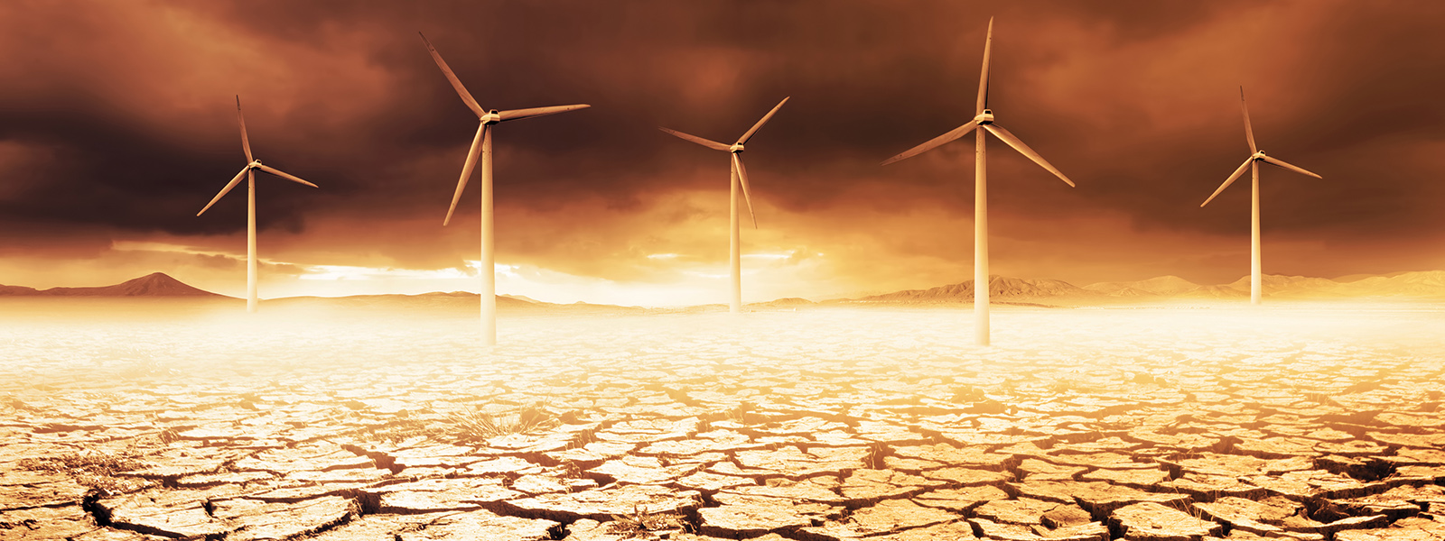Wind turbines on a cracked earth desert.