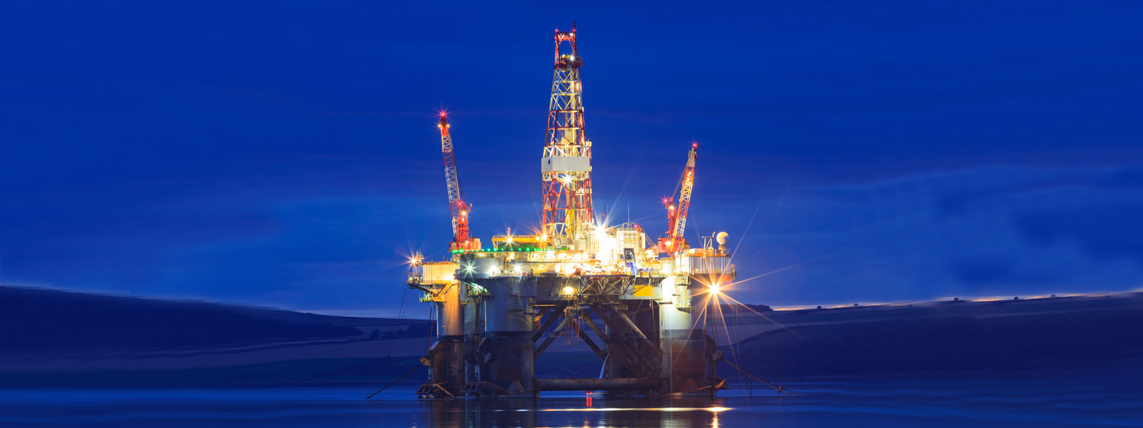 oil rig in the north sea at dusk lit up by lights
