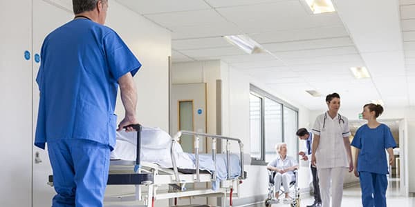 Hospital corridor with doctors and nurses walking through, and a patient being pushed on a trolley