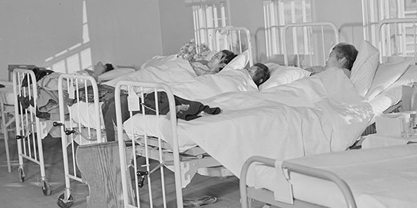 Old black and white image of patients in hospital beds