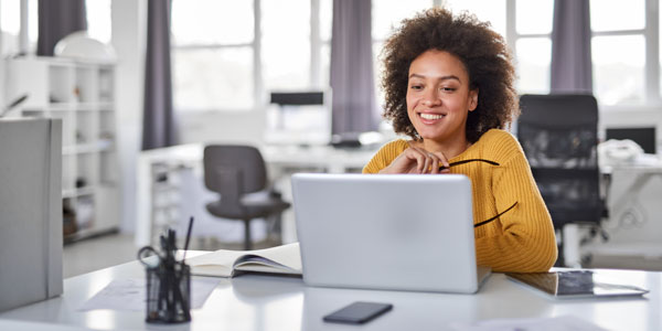 A young woman sits working at a computer in her workplace