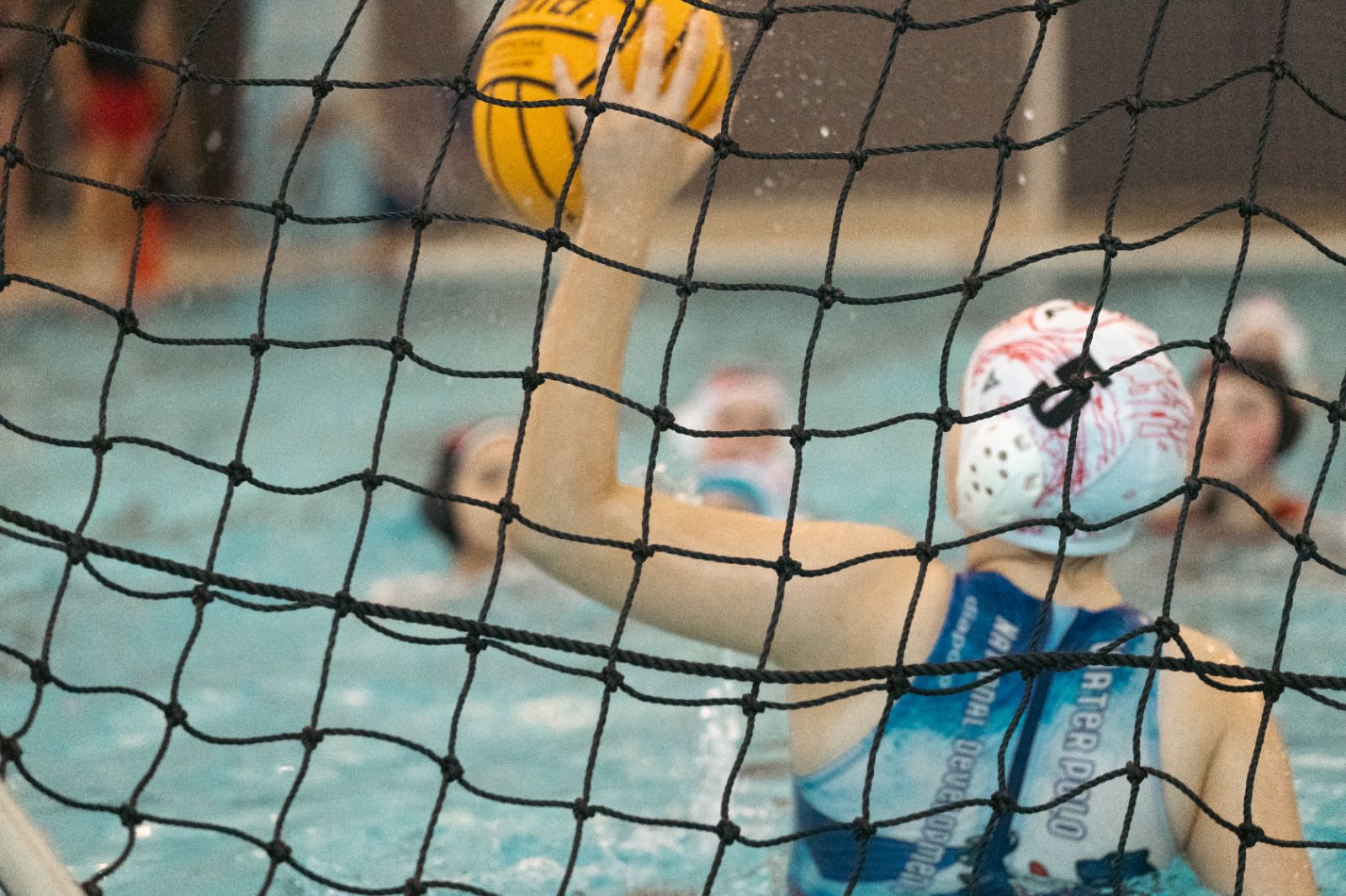A female water polo player defending the goal. 