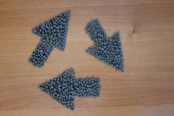 Three arrows made of small plastic granules, layout like the recycling symbol.