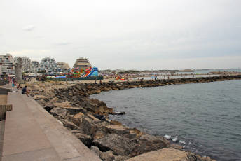 Coastal area with breakwater rocks in the foreground and colourful bouncy castles in the background.