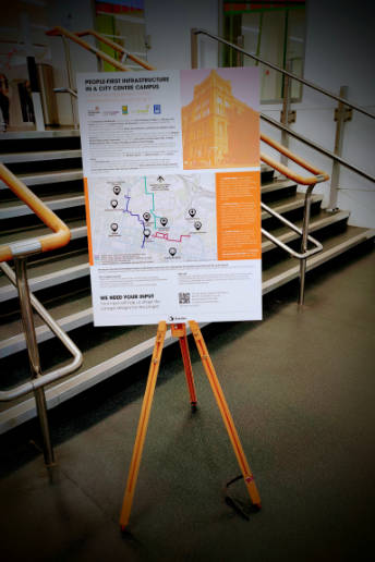 A display board related to active travel is in front of some stairs.