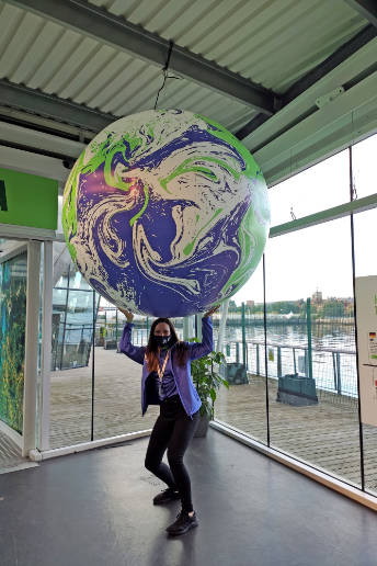 The author of the image holds a very large globe above her head showing ocean currents. 